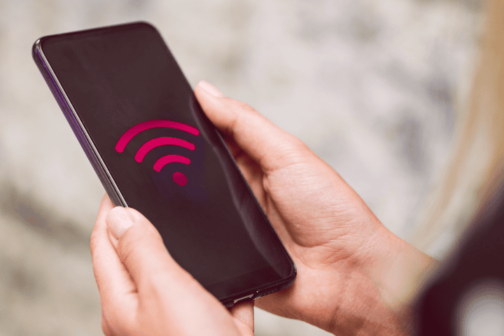 Imagem de uma mão segurando um celular, com o símbolo de Wi-Fi na tela.