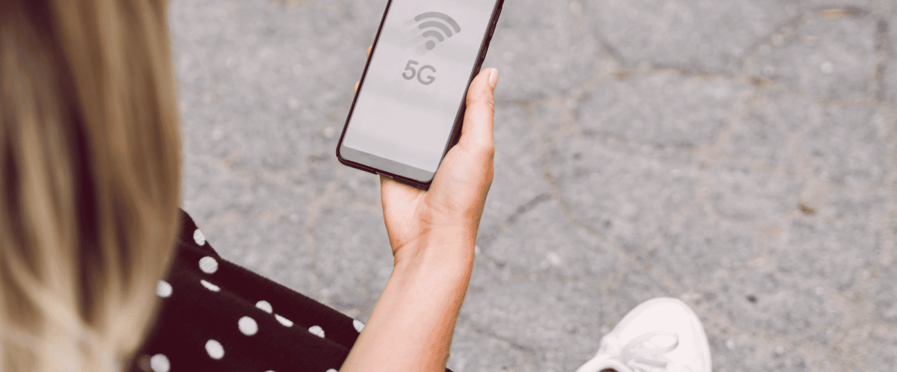 Mulher segurando celular com o símbolo de 5G na tela